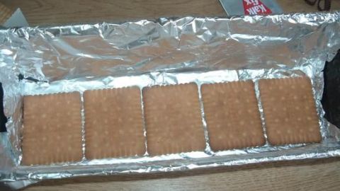 Ein Kuchen aus Keksen liegt in einer Alufolie, bereit zur Zubereitung des Kalten Hundes.