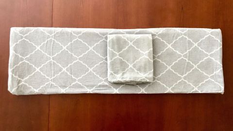 Eine dekorative Bettwäsche liegt ordentlich auf einem Holztisch und zeigt ein geometrisches Muster zur praktischen Aufbewahrung.