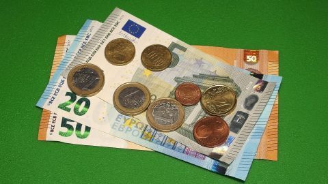 Münzen und Geldscheine liegen auf einer grünen Unterlage, was zur besseren Einteilung des Geldes anregt.