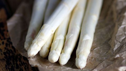 Woran erkennt man frischen Spargel? Lies jetzt diesen Tipp, er verrät dir, wie leicht du es herausfinden kannst. Weiße Spargelstangen liegen auf braunem Papier und werden aneinander gerieben, um Frische zu erkennen.
