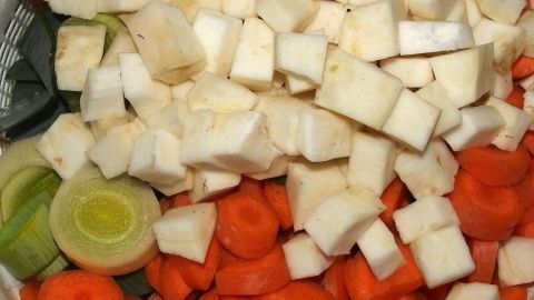 Bunte, gewürfelte Gemüsewürfel aus Karotten, Sellerie und Lauch liegen sauber nebeneinander in einer Schüssel, bereit für die Herstellung von Gemüsesalz.
