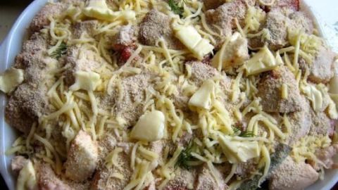 Gebackene Hühnerbrustfiletstückchen sind mit Käse und Gewürzen überbacken und warten in einer Auflaufform auf den Servierzeitpunkt.