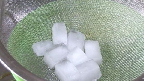 Eiswürfel liegen in einem Sieb und schmelzen langsam über einer Schüssel, während das Wasser sich sammelt.