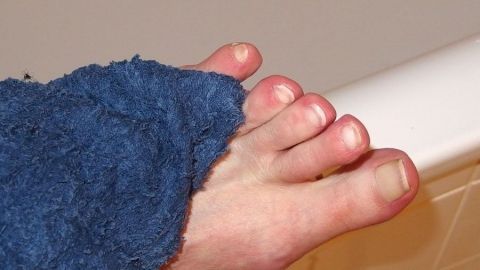 Ein Fuß, eingewickelt in ein Handtuch, berührt die Badewanne, er vermittelt das Thema Fußpflege und Hygiene.