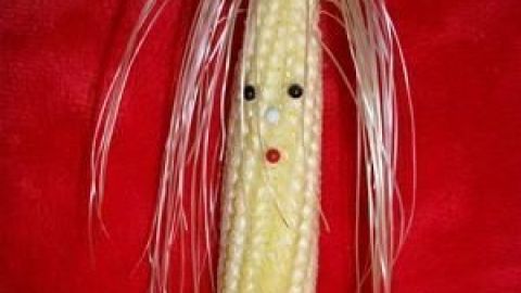Mit etwas Kreativität kannst du aus Maiskolben eine charmante Küchendeko basteln. Diese Figur bringt nicht nur Farbe, sondern auch Persönlichkeit in deinen Raum. Lass dich von den Ideen im Artikel inspirieren! Ein Maiskolben mit Haaren aus Stroh und Gesichtszügen steht vor einem roten Hintergrund und dient als kreative Küchendeko.
