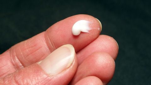 Eine Hand hält eine kleine Menge Nivea Creme, die auf dem Finger balanciert, um verstopfte Nase zu lindern.