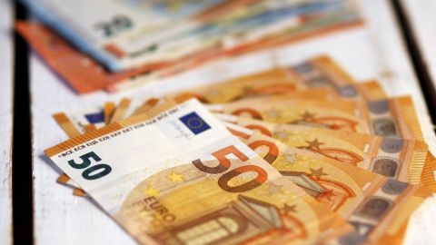Haufen von Euro-Scheinen liegt auf einem Holzuntergrund, um Haushaltsgeld über den Monat besser zu strecken.