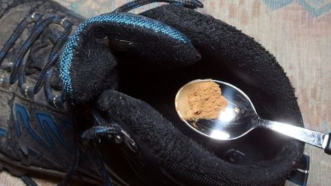 Etwas gemahlenen Zimt in die Schuhe streuen. Täglich. Nach kurzer Zeit gewinnt der Zimt die Oberhand, denn Zimt killt die Stinkbakterien und überdies wirkt Zimt auch gegen Fußpilz. Ein schwarzer Schuh hält einen Löffel mit einer Portion Zimt, umgeben von einem weichen Teppichboden.