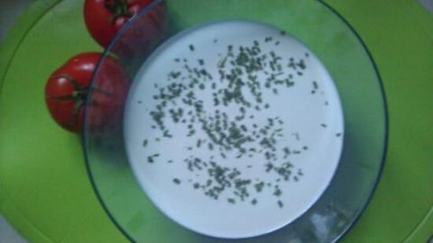 Eine Schüssel mit Aioli ist von frischen Tomaten umgeben und auf einem grünen Untersetzer platziert, perfekt für einen Snack.