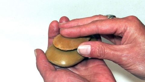 Wenn man den alten Rest einer Seife auf die neue Seife drückt, lässt die sich einfach & vollständig verbrauchen. Zwei Hände halten eine Seife, während sie diese sanft reiben, um den Schaum zu erzeugen und Wasser zu sparen.