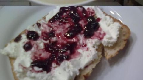Selbstgemachter Frischkäse befindet sich in einer Schüssel, wird auf Brot serviert und mit Marmelade und Gemüse dekoriert.