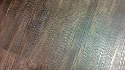 Ein dichter Holzboden zeigt feine, knarrende Oberflächenmerkmale in einem alten Haus, das eine nostalgische Atmosphäre vermittelt.