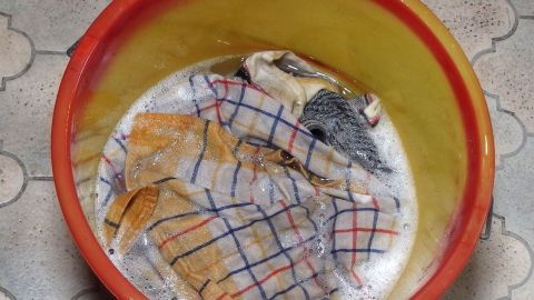 In einem Eimer mit Wasser sind verschmutzte Wäscheteile zur Entfernung von Kettenschmiere eingelegt, um sie zu reinigen.