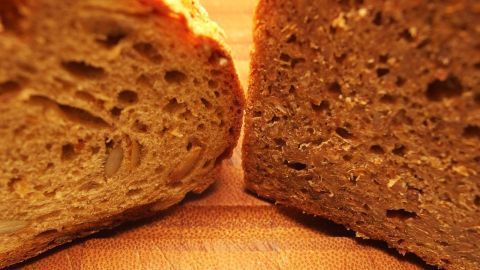 Zwei Schnittstücke Brot liegen auf einem Holzbrett, frisch geschnitten, bereit, um mehrere Tage frisch gehalten zu werden.