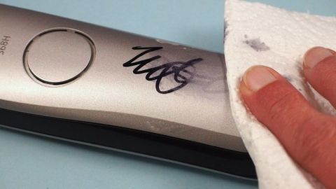 Ein Handtuch entfernt Edding-Marker von einer glatten, metallischen Oberfläche in einem hellen Umfeld.