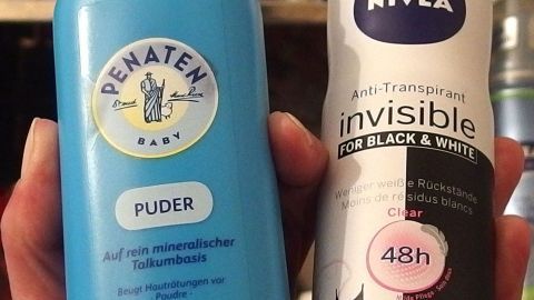 In der Hand hält jemand ein Baby-Puder und ein Deo, um die Alternative Babypuder statt Deo zu zeigen.