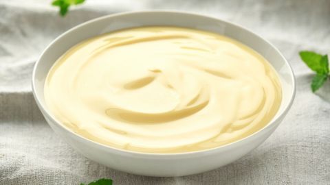 Eine Schüssel mit cremigem Apfelmus steht auf einem hellen Tuch, umgeben von frischen Minzblättern.