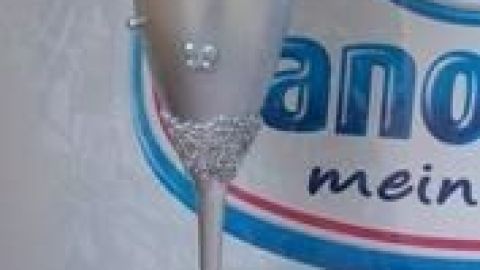 Diese kreative Dekoration aus einem Sektglas verbindet Eleganz mit Individualität. Der glitzernde Glaskörper und die floralen Akzente verleihen jedem Raum eine besondere Note. Perfekt für festliche Anlässe! Ein Sektglas mit glitzernden Verzierungen steht dekorativ in einem eleganten Umfeld, geschmückt mit einer Blume oben drauf.