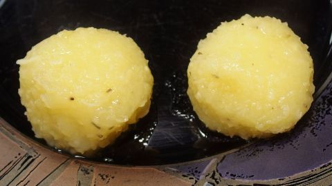 Runde, gelbe Klöße schwimmen in einem dunklen Topf und zeigen eine perfekte Form beim Kochen, ohne zu zerfallen.
