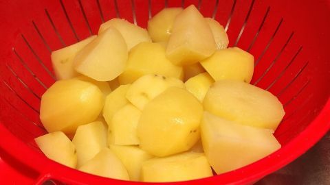 Angebrannte Kartoffeln? Das kann doch jedem mal passieren. So kann man die Kartoffeln noch retten. In einem roten Sieb liegen geschnittene Kartoffeln, die darauf warten, zum Kochen oder Braten vorbereitet zu werden.