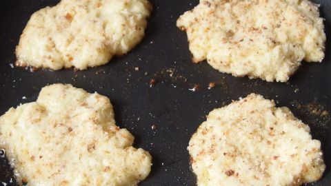 Frittierte Kartoffelpüree-Wreste liegen goldbraun in einer Pfanne und brutzeln in heißem Öl.
