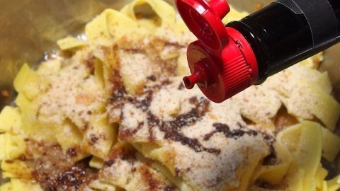 Nudeln mit Paniermehl werden aus einer Schüssel heraus mit Maggi gewürzt, um ein einfaches und leckeres Gericht zu kreieren.