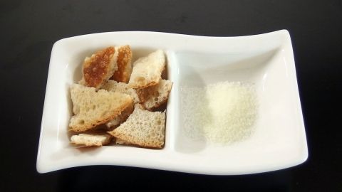 Eine weiße Schale mit Brotwürfeln und Gewürzen, bereit zum Reinigen und Zubereiten von Speisen.