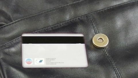 Ein Geldbeutel liegt auf schwarzem Leder, und ein Magnetverschluss ist sichtbar. Achte auf die Nähe des Kartenlesers.