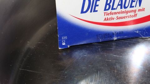 Zahnprothesenreinigungstabletten helfen auch, Angebranntes in Töpfen zu lösen und erleichtern die Reinigung. Ein glänzender Topf steht bereit, während Gebissreiniger zur effektiven Reinigung von angebranntem Material verwendet wird.