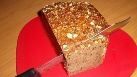 Ein rundes Brot liegt auf einem roten Untersetzer, während ein Messer bereit ist, es aufzuscheiden.