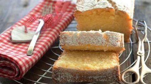 Lockerer Rühr- oder Sandkuchen gelingt dir perfekt mit einfachen Tipps: Achte auf die richtige Mischung von Butter, Zucker und Eiern. Das Ergebnis ist ein fluffiger Kuchen, der auf dem Kuchengitter zum Genießen einlädt. Ein Sandkuchen liegt auf einem Kuchengitter, aufgeschnitten. Daneben ein rot kariertes Tuch mit Gabel und Messer.