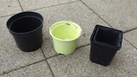 Blumentöpfe & Paletten bei Gärtnereien abgeben & Abfall vermeiden. Drei Blumentöpfe stehen auf einem glatten Boden, bereit zur Abgabe in einer Gärtnerei für das Abfall vermeiden.