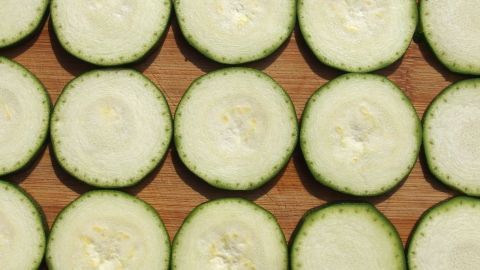 Zucchini-Scheiben sind ordentlich auf einem Holzbrett angeordnet, bereit zum Vorbereiten für das Einfrieren.