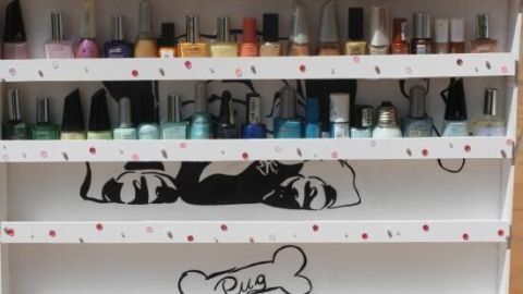 Nagellackregal zeigt bunte Nagellackflaschen, geordnet auf einem weißen, gepunkteten DIY-Regal mit Hundezeichnung.