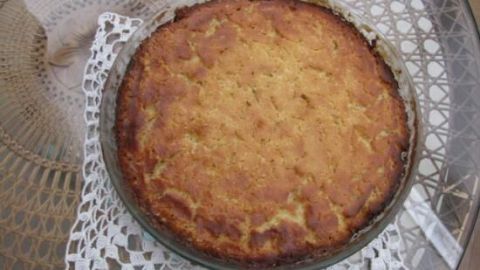 Ein runder Butterkuchen liegt auf einem filigranen Spitzenuntersetzer und strahlt frisch gebacken und goldbraun.