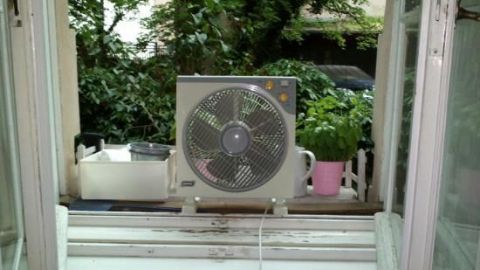 Ein Ventilator steht auf dem Fensterbrett und bläst kühle Luft in die Wohnung, um Hitze draußen zu halten.