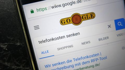 Ein Smartphone zeigt eine Google-Suche nach "telefonkosten senken". Im Hintergrund sind Suchoptionen und Ergebnisse sichtbar.