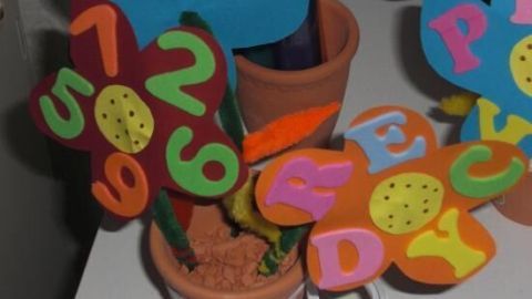 Bunte Pappblumen stehen in einem Tontopf und sind kreativ für den Schulanfang dekoriert.