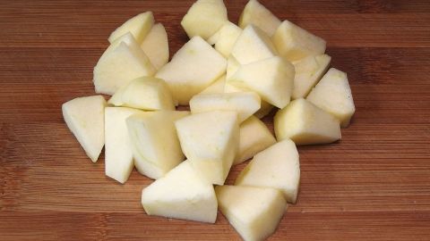 Würfelförmige Apfelstücke liegen auf einem Holzbrett, bereit zum Einfrieren, um die Frische zu bewahren.