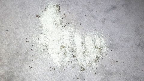 Verschüttetes Öl mithilfe von Katzenstreu leichter aufputzen. Ein grauer Untergrund zeigt einen schmutzigen Fleck mit öliger Substanz, die unordentlich verteilt und leicht verschmutzt ist.