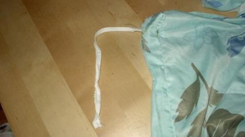 Ein Stück Microfaser-Bettwäsche liegt auf einem Holzboden, mit einem weißen Kordelband sichtbar, das für Fixierung sorgt.