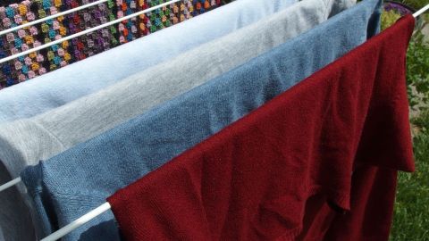 Bunte Wäsche hängt zum Trocknen auf einem Wäscheständer im Freien, kann nach 40 Grad-Wäsche muffig riechen.