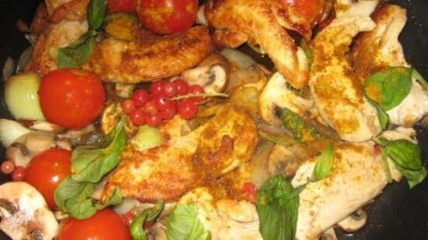 In der Pfanne braten Hähnchenbruststücke zusammen mit frischen Tomaten, Johannisbeeren und Kräutern.