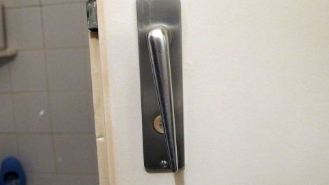 Ein Türgriff aus Edelstahl an einer weißen Tür, der anscheinend nicht mehr betätigt werden kann.