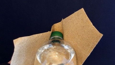 Eine Flasche mit fest sitzendem Schraubverschluss wird mit einem Tuch gehalten, um den Verschluss zu öffnen.