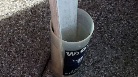 Ein Plastik Trinkbecher steht auf dem Boden und h&auml;lt einen Holzstab, um Ameisen beim Grillen abzuwehren.