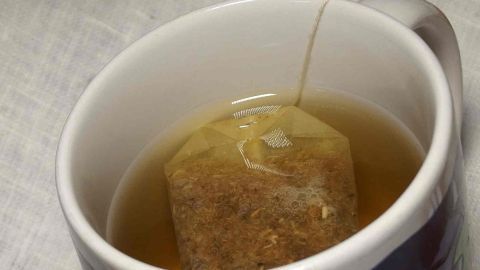 Eine Tasse mit Kamillentee zieht im warmen Wasser, um das blonde Haar auf natürliche Weise aufzuhellen.