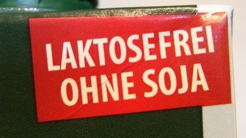 Ein rotes Etikett auf einem Produkt, das "Laktosefrei ohne Soja" anzeigt, deutet auf spezielle Ernährung hin.