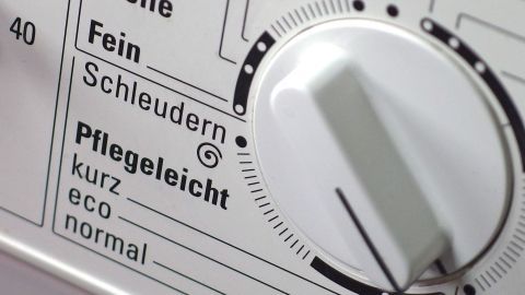 Ein Waschmaschinenregler zeigt die Einstellungen „Pflegeleicht“ und „Fein“. Die Umgebung ist der Bedienfeldbereich der Maschine.