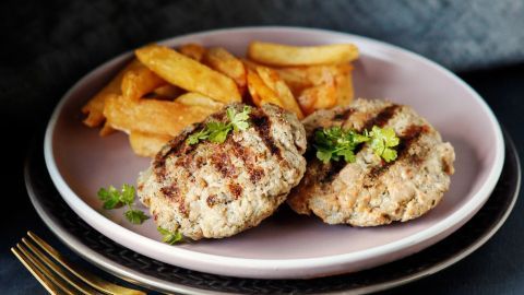 Saftige Frikadellen aus Putenfleisch liegen auf einem Teller, begleitet von knusprigen Pommes frites.